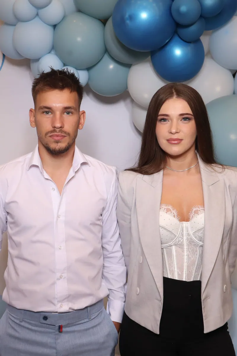 Fotografia făcută la cabină, înainte de transformare — doi invitați în fața unui decor cu baloane